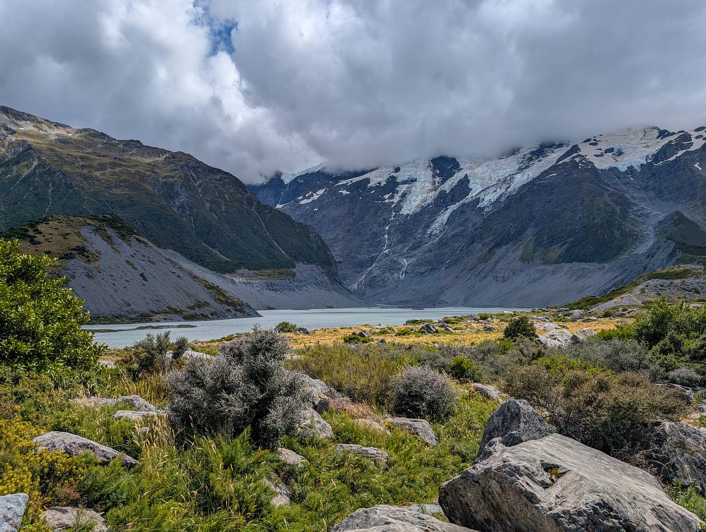 glacial lake and mountains with rocks in foreground