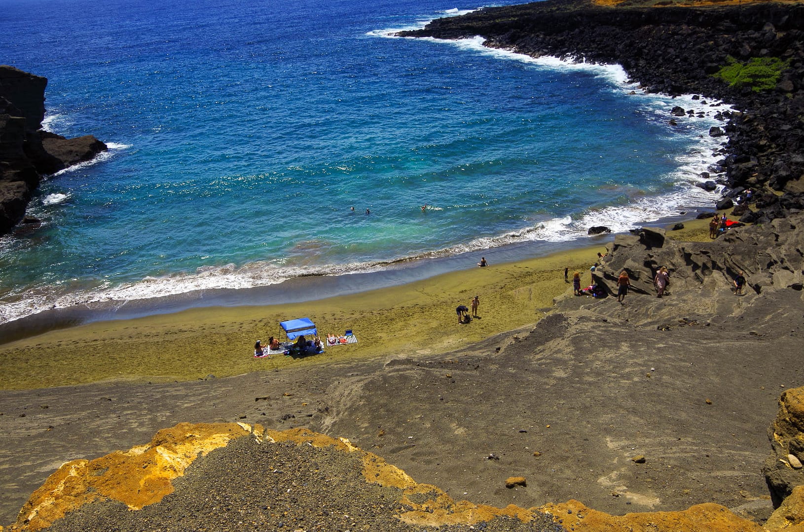 view from cliff over green sand beach