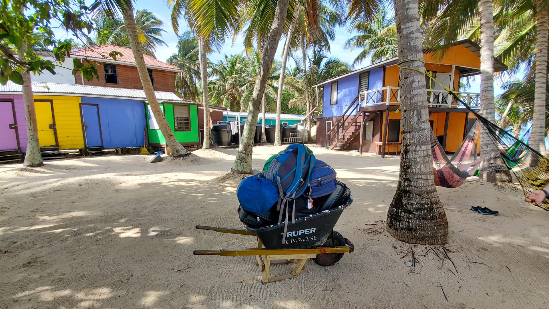 baggage in a wheelbarrow in front of colorful huts