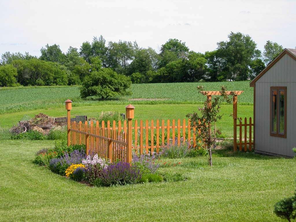 wood fence and pergola next to shed with small tree