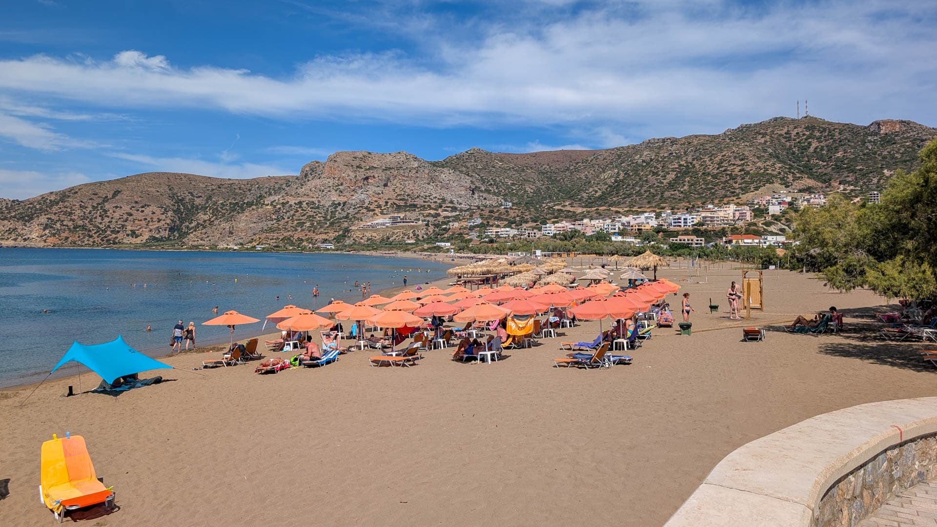 sunbeds and umbrellas on beach with mountains beyond